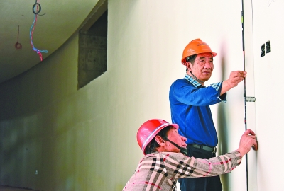 李旺平和技术人员正在检测墙面的平整度。